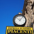 Uhr an der Piazza Cavour mit Werbung für ein Bestattungsunternehmen