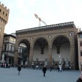 Loggia dei Lanzi in Florenz an der Piazza della Signoria. Links davon steht vor dem Palazzo Vecchio eine Kopie von  Michelangelos David.